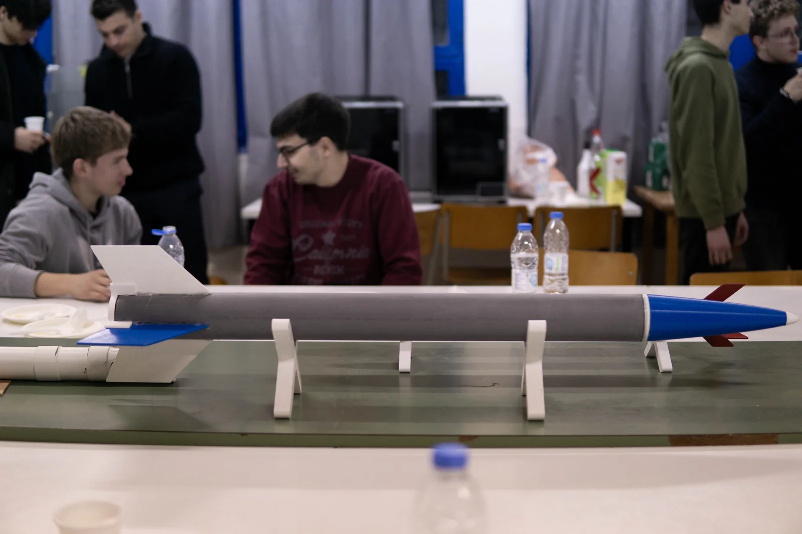 A rocket on stands and HEPHAESTUS members in the workshop